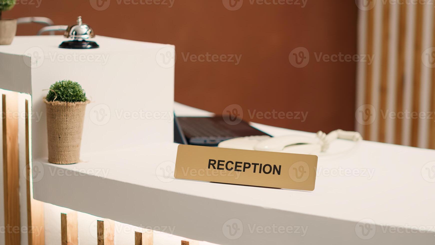 Close up of elegant modern stylish hospitality industry lounge hotel lobby check in desk. Empty welcoming resort lobby reception counter with concierge bell next to mini plant photo