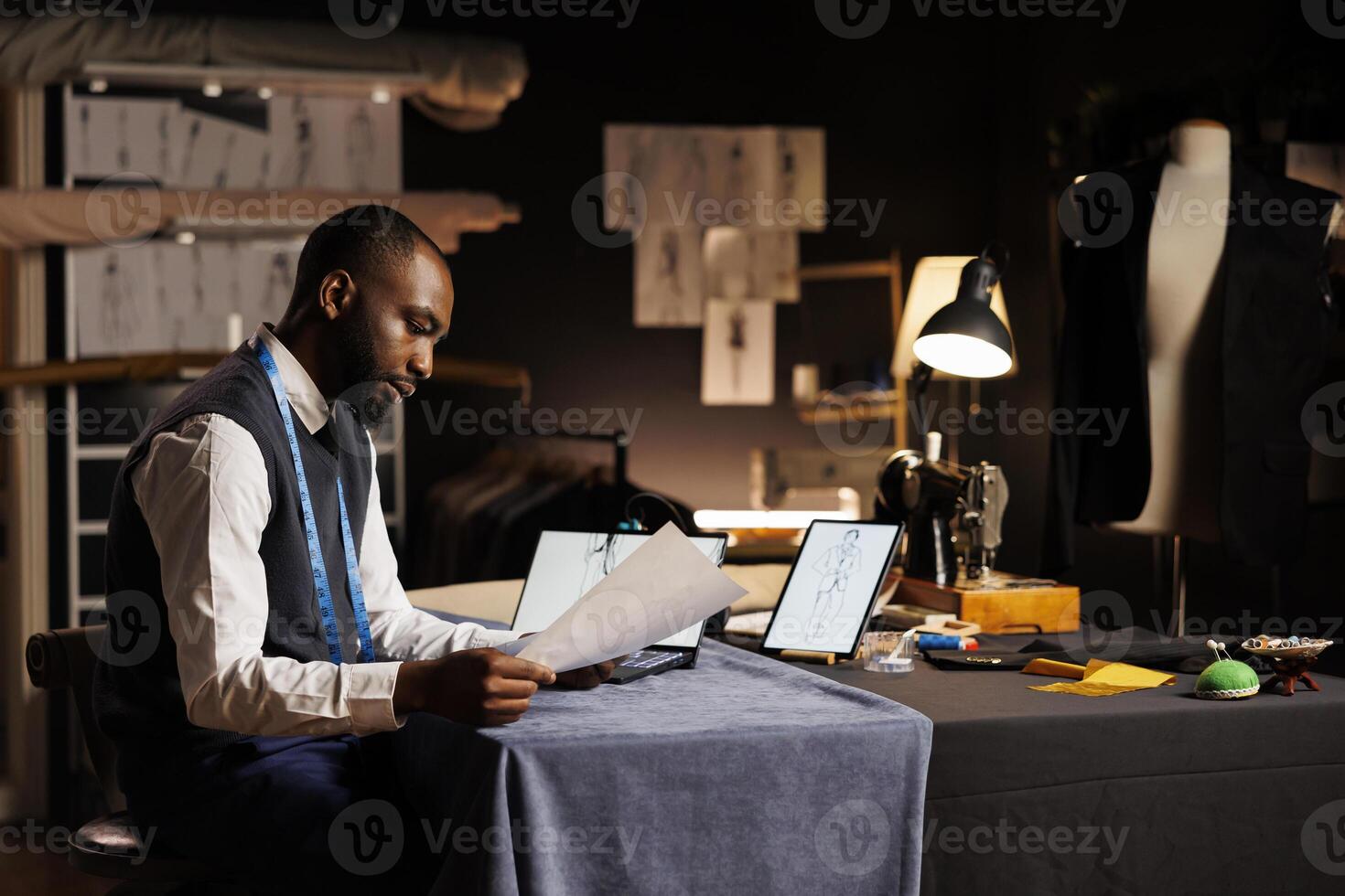 African american fashion designer conceptualizing custom made sartorial collection for upcoming runway show. Creative dressmaker handdrawing sketch of bespoke garments in tailoring studio photo