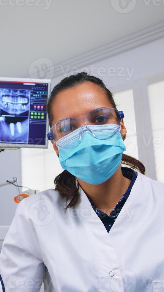 pov de dentista trabajando en paciente boca hygine en dental oficina comprobación dientes problemas. médico examinando en ortodoncia oficina con ligero lámpara y esterilizado utensilios, de cerca cara en médico mascarilla. foto