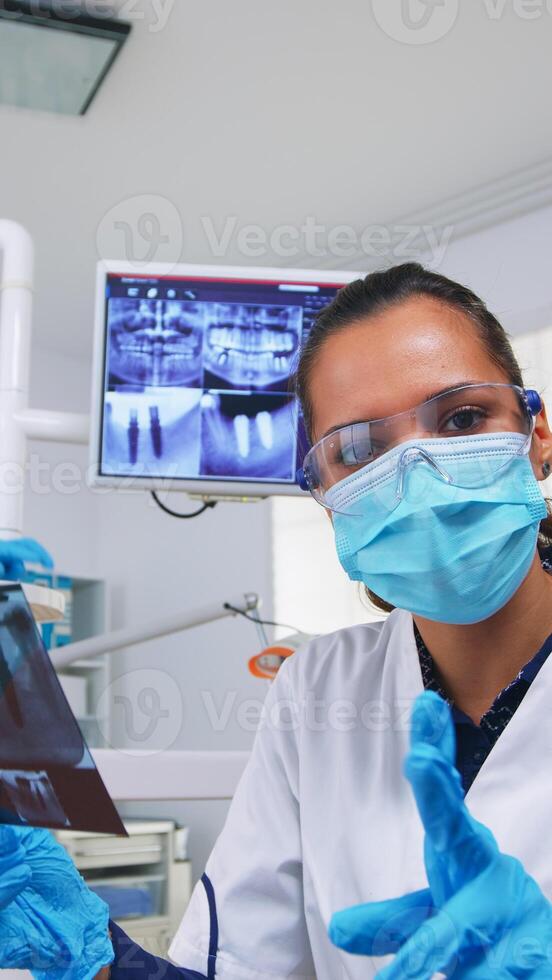 paciente pov mirando a dentista preguntando para dental radiografía demostración dientes imagen. estomatología especialista vistiendo protector mascarilla, trabajando en moderno estomatológico clínica, explicando radiografía de diente foto