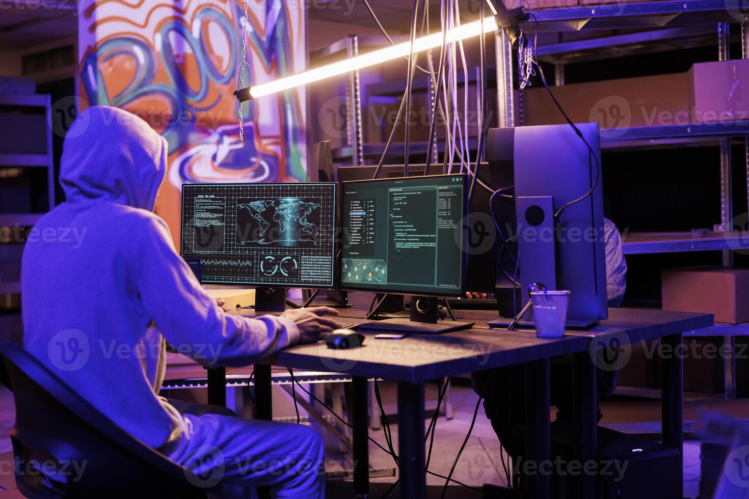 Hacker in hood gathering information using illegal spyware on computer to break into server. Criminal doing web tracking with malicious software and checking data on screen photo