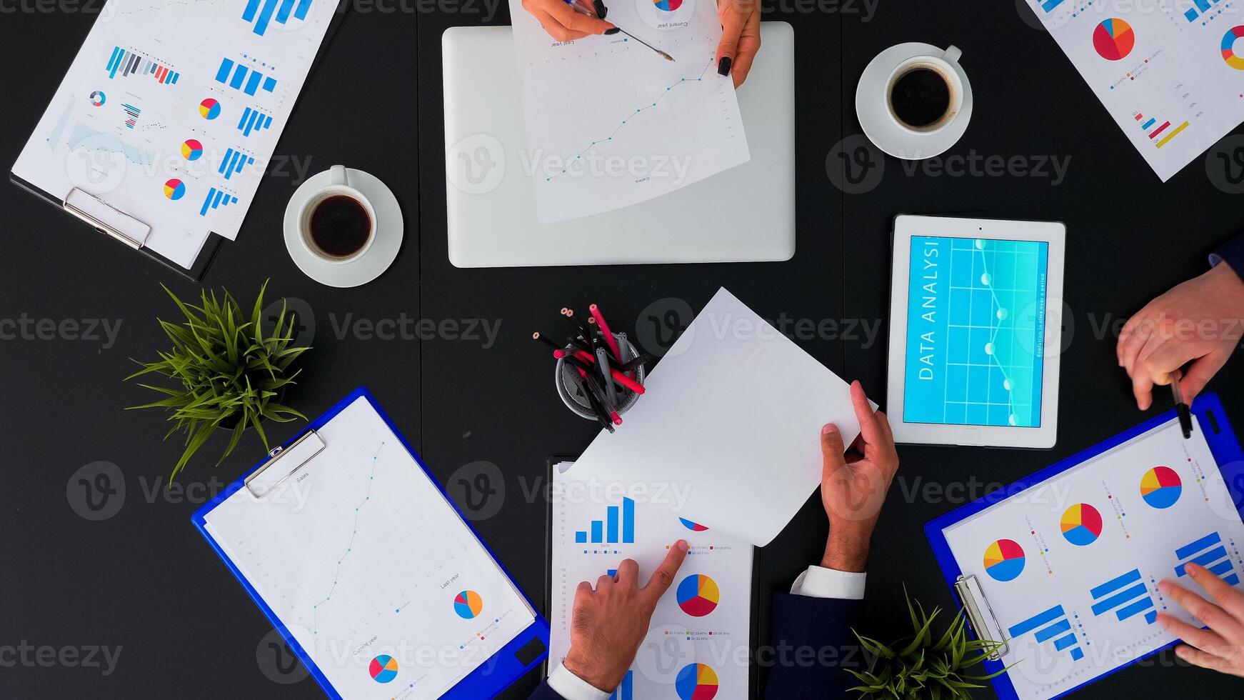 Top view of fast forward shot of people brainstorming financial statistics graphs planning next project using modern technology. Working in conference room with annual reports document on table. photo