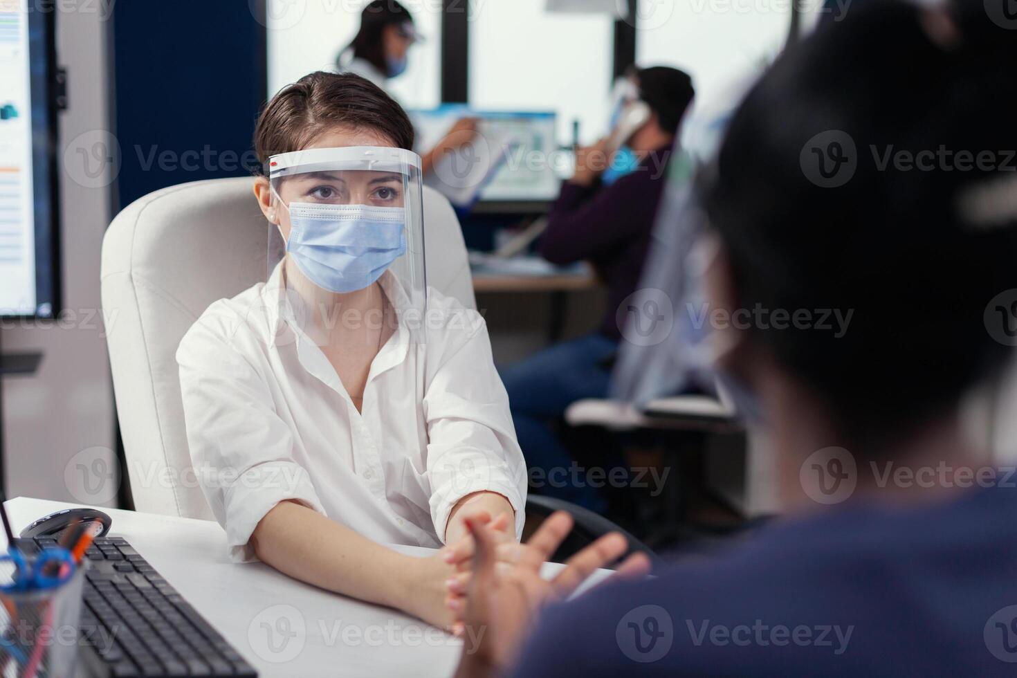 Manger wearing face mask during job interview with african woman. Multiethnic team working in company with new normal respecting social distance because of global pandemic with coronavirus. photo