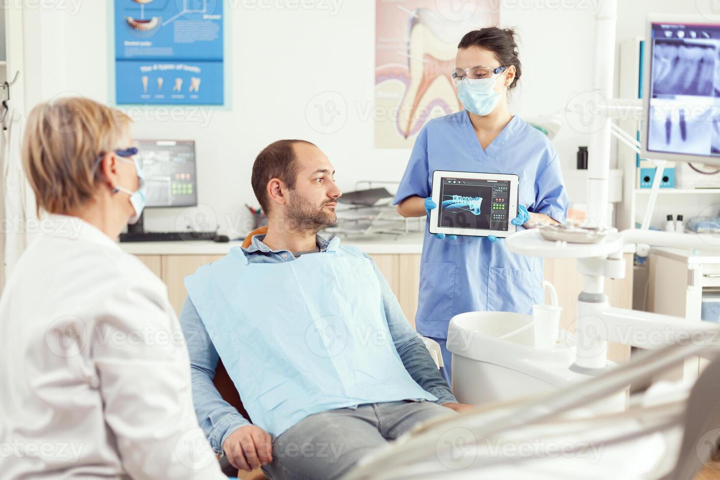 dentista asistente demostración dientes radiografía en tableta ordenador personal computadora pantalla a enfermo paciente hombre a dental clínica oficina. ortodoncista que se discute dolor de muelas tratamiento a evitar estomatología problemas foto