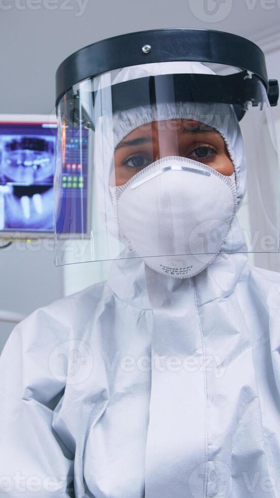 Dentist pov in covid suit examining mouth hygine using dental tools in stomatological office with new normal. Stomatolog wearing safety gear against coronavirus during heatlhcare check of patient. photo