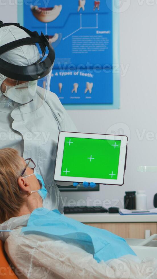 Dentist with face shield pointing at green screen display during coronavirus epidemic. Explaining using monitor with chroma key izolated chroma pc key mockup greenscreen display mock-up touchscreen photo