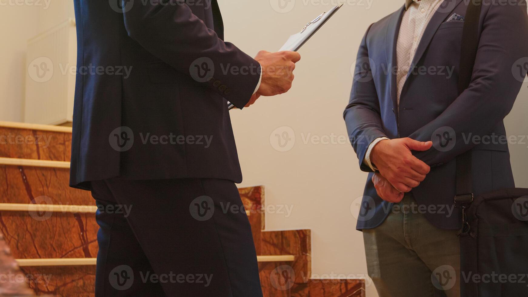 Close up of two business men in suit shaking hands standing on company stairs talking. Group of professional successful businesspeople working in modern financial workplace. photo