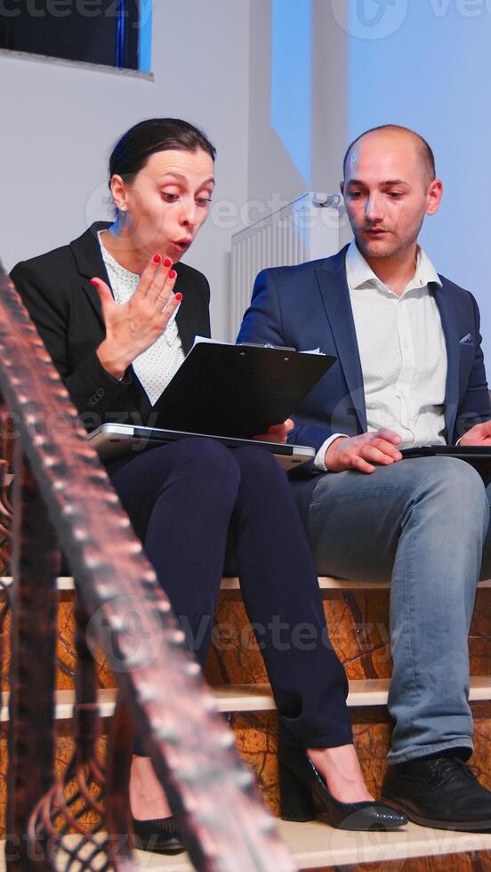 descontento mujer de negocios discutiendo empleado trabajando tiempo extraordinario en irrespetado fecha límite proyecto sentado en escalera en corporativo edificio. nervioso, cansado, estresado empresario explicando Finanzas importancia foto