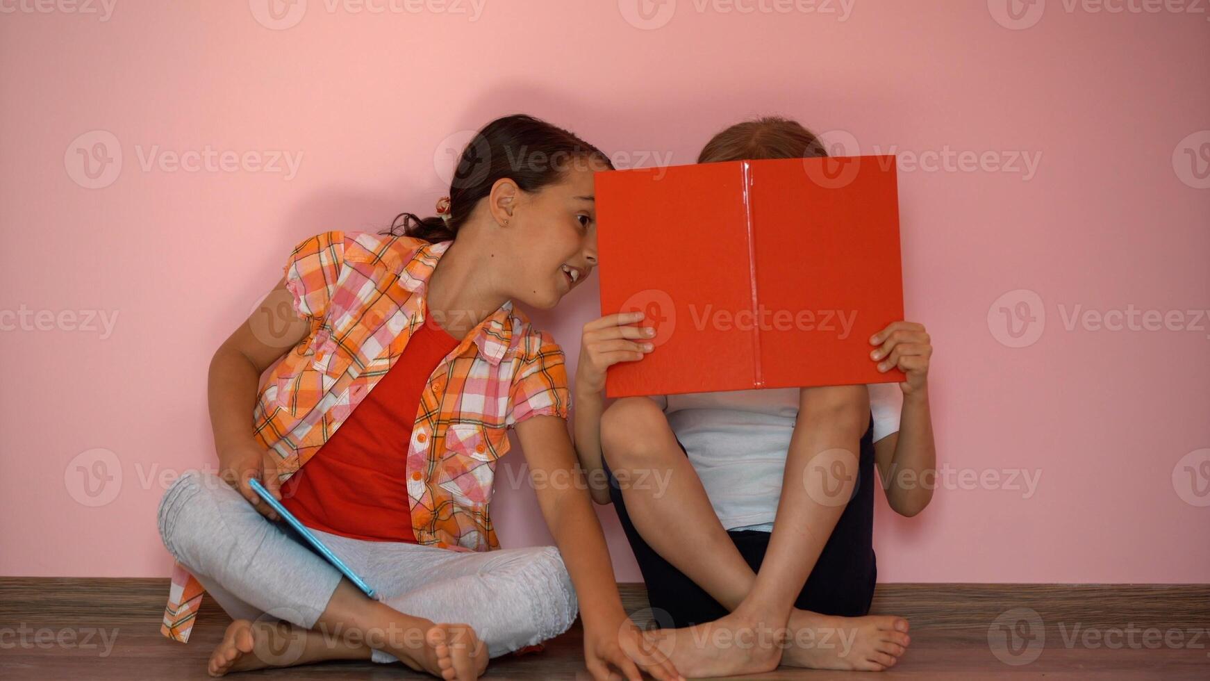 Little girls reading a book in living room. Smart schoolgirls doing their homework after school. Education and distance learning for kids. Homeschooling during quarantine. Stay at home entertainment. photo