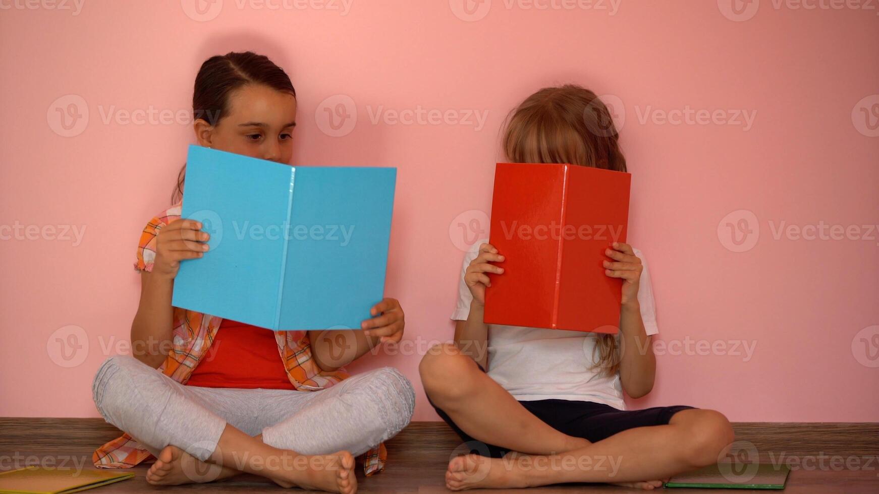 Little girls reading a book in living room. Smart schoolgirls doing their homework after school. Education and distance learning for kids. Homeschooling during quarantine. Stay at home entertainment. photo