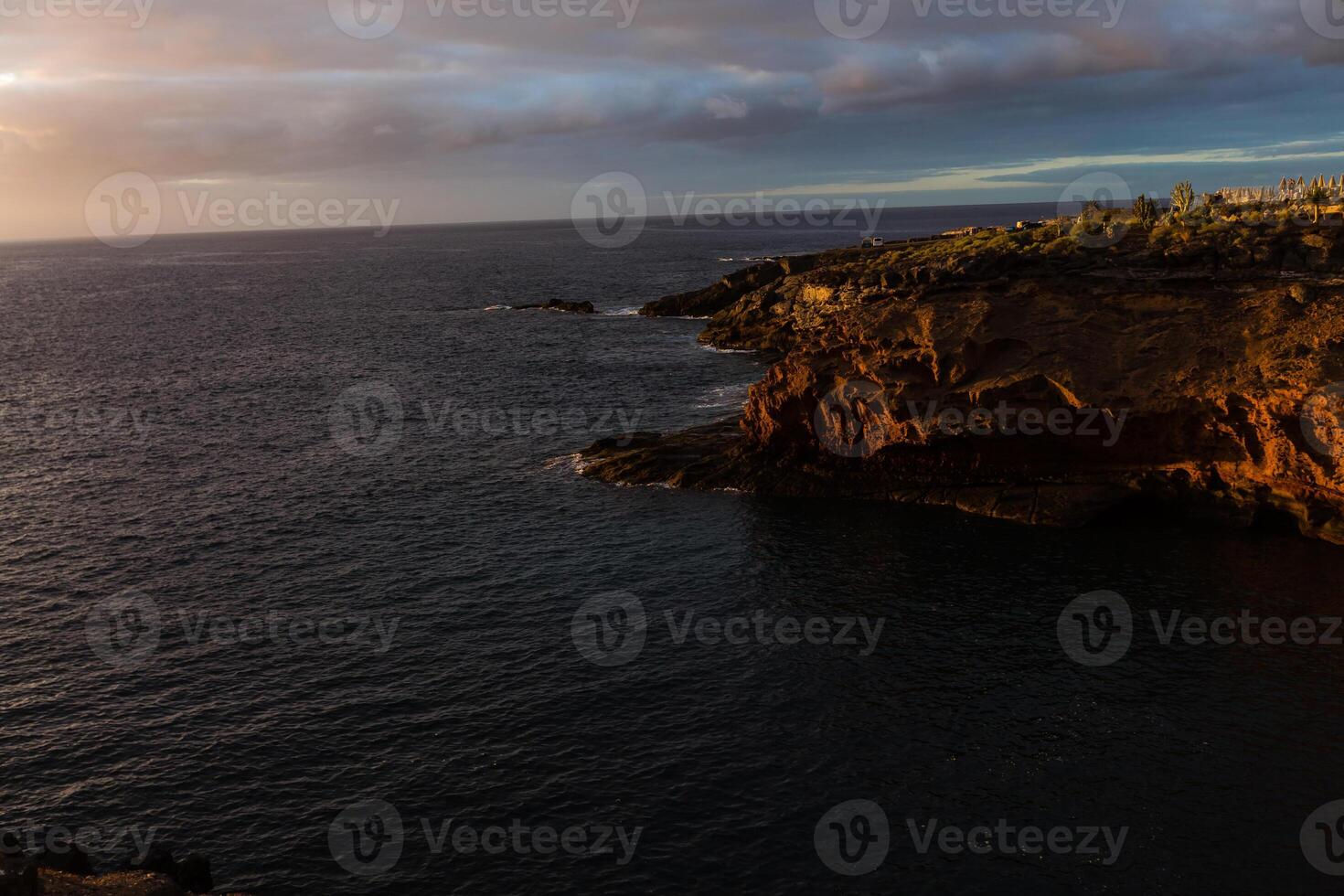 Panoramic view of the Illuminated Las Americas at night against the colorful sunset sky with lights on the horizon on Tenerife island, Spain photo