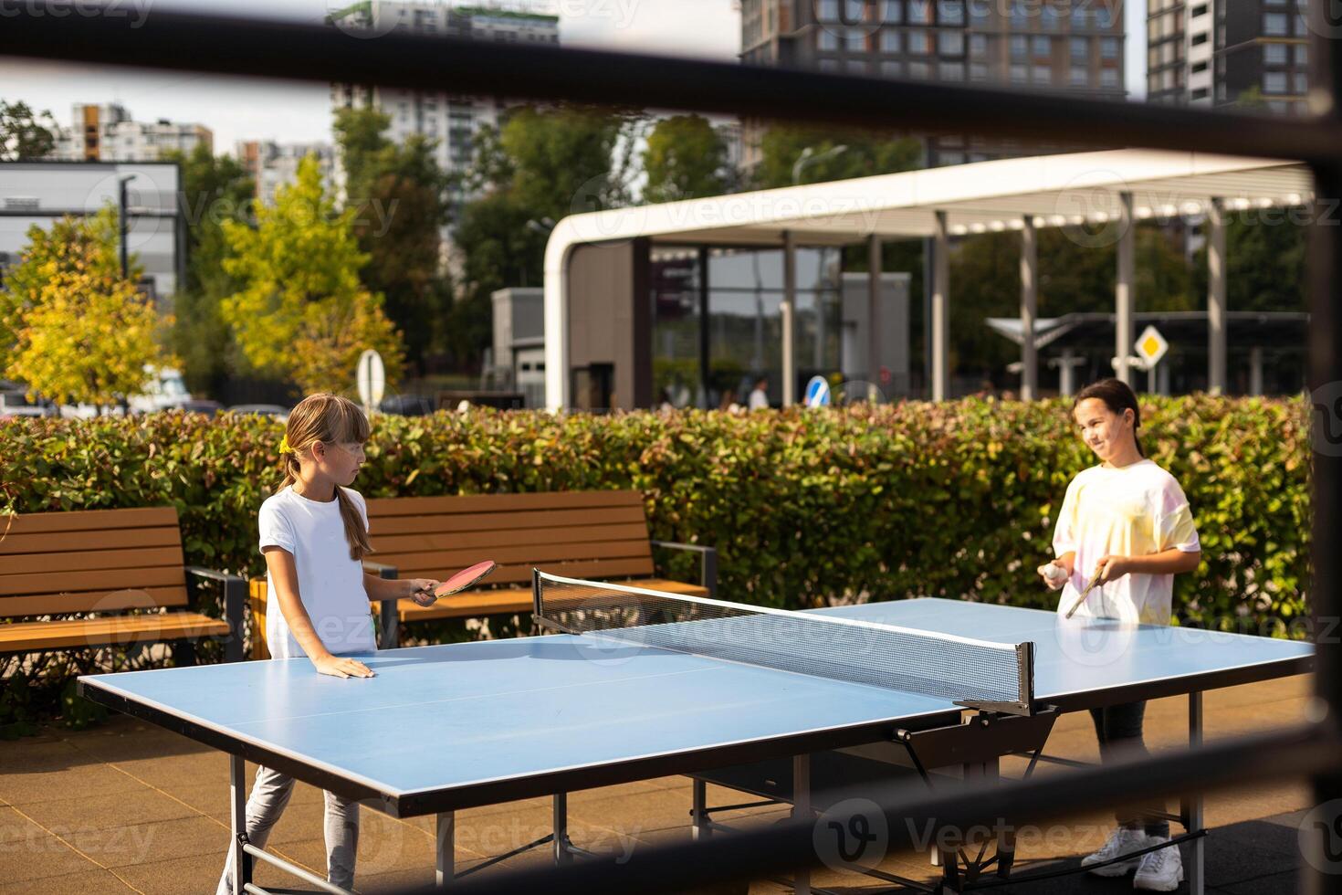 Photography of table tennis area in the public park. Street ping-pong sports competitions in spring day. Lifestyles of big city. People playing taBle tennis actively. photo