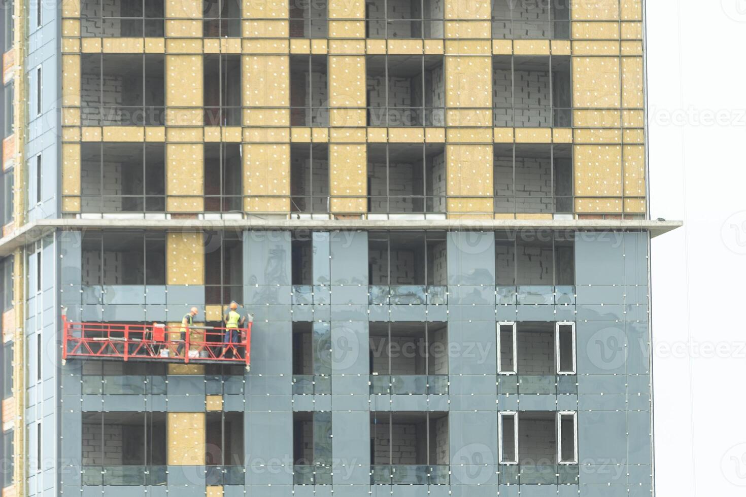 Construction cradle on a building at a height with workers. Work at height in a construction cradle photo