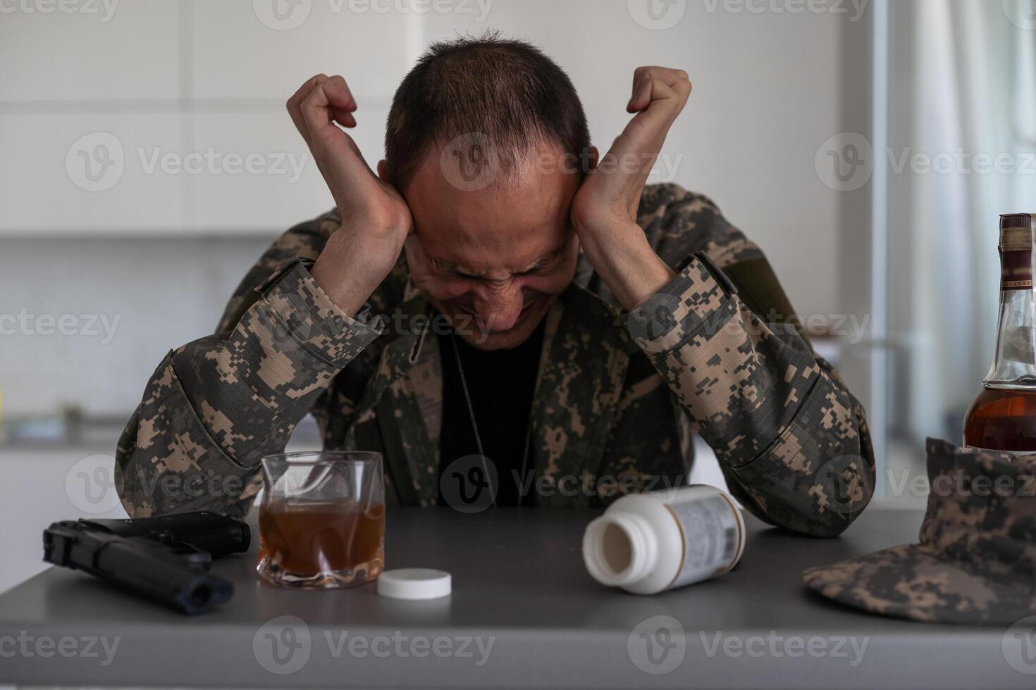 A man in camouflage suffers from depression after returning from the army. He uses alcohol and narcotic tablets. He is tormented by heavy memories. photo