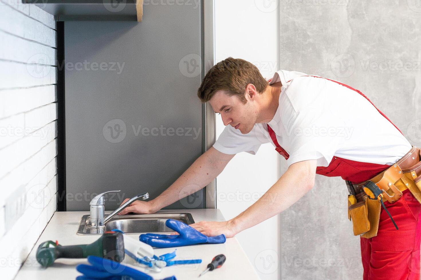 Male plumber repair sink faucet at client home. Man mechanic or repairman fix pipeline at customer kitchen. Good quality plumbing company service. Maintenance and household assistance concept photo