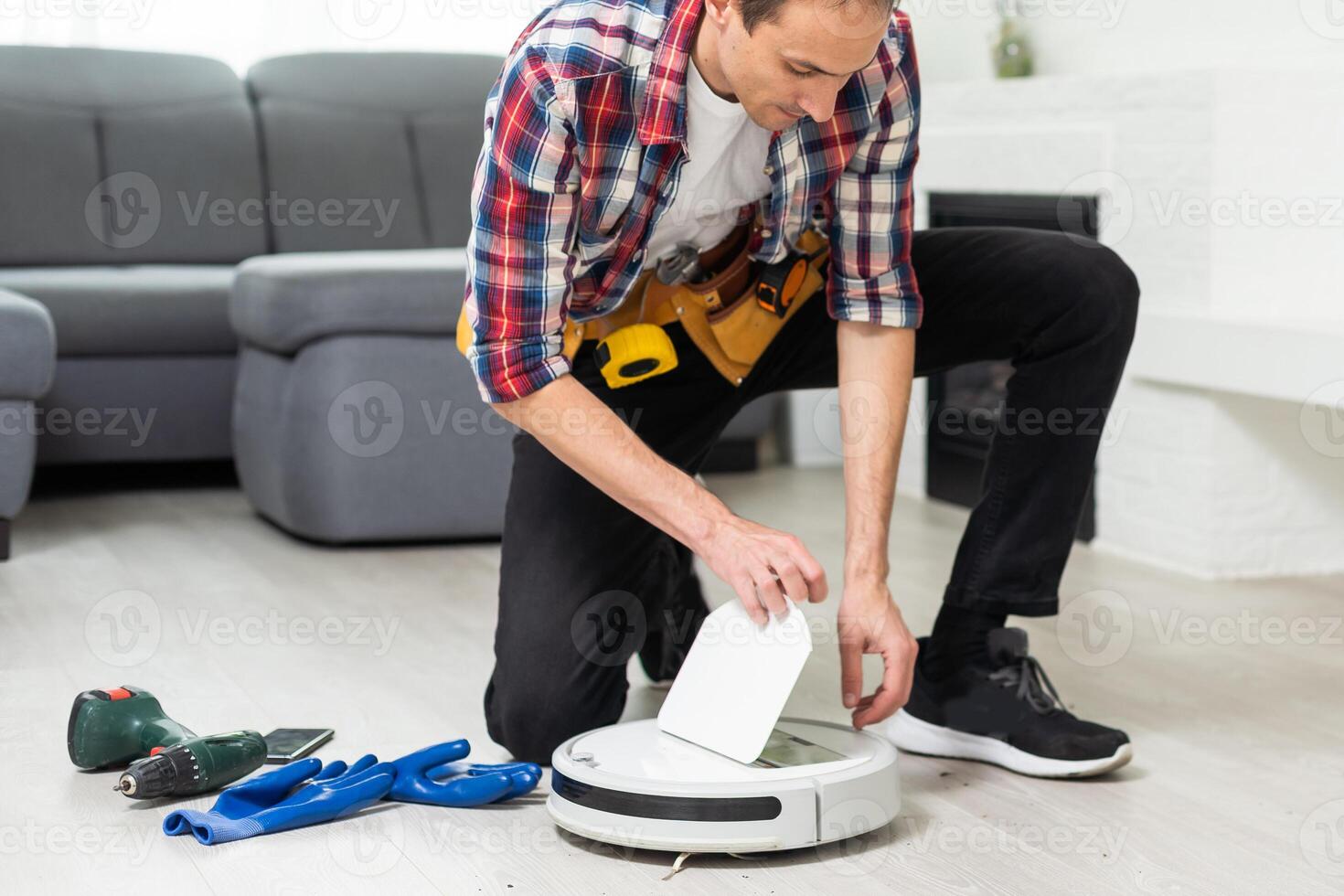 A man is fixing robot vacuum cleaner by hand holding screwdriver to open the cover. Consumables for a robot vacuum cleaner. photo