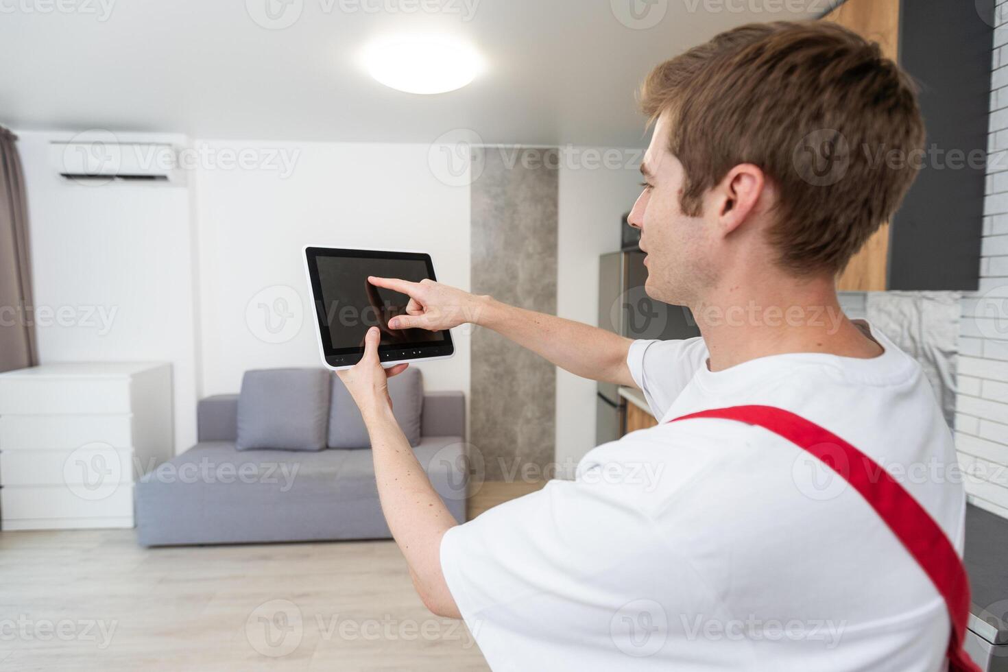 Worker with tablet computer checking alarm system indoors. photo