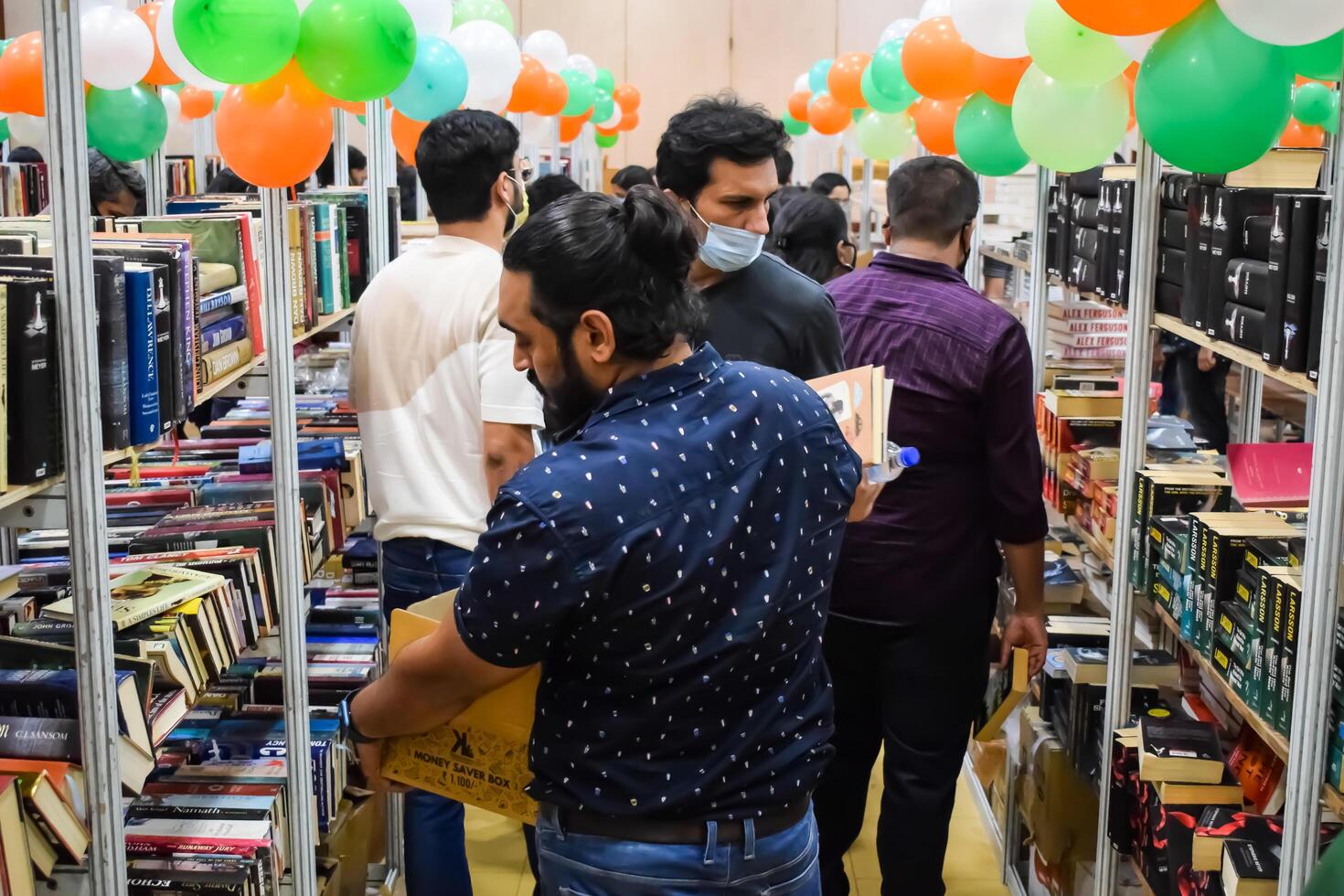 Delhi, India, February 17 2024 - Various age group people reading variety of Books on shelf inside a book-stall at Delhi International Book Fair, Books in Annual Book Fair at Bharat Mandapam complex photo