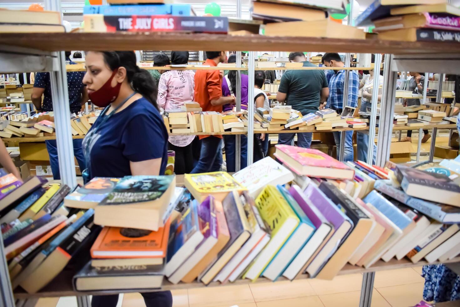 Delhi, India, February 17 2024 - Various age group people reading variety of Books on shelf inside a book-stall at Delhi International Book Fair, Books in Annual Book Fair at Bharat Mandapam complex photo