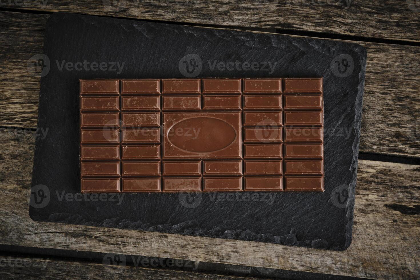 Bar milk chocolate on a black slate. photo