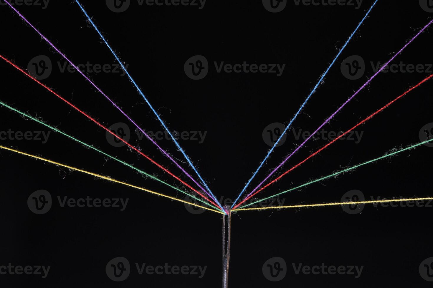 Eye sewing needle and multicolored threads passed through it black background. Concept hobbies and crafts. photo