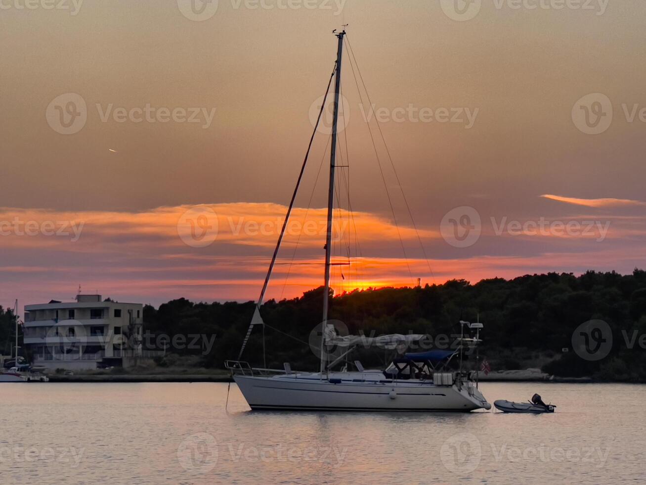 a sailboat is anchored in the water at sunset photo