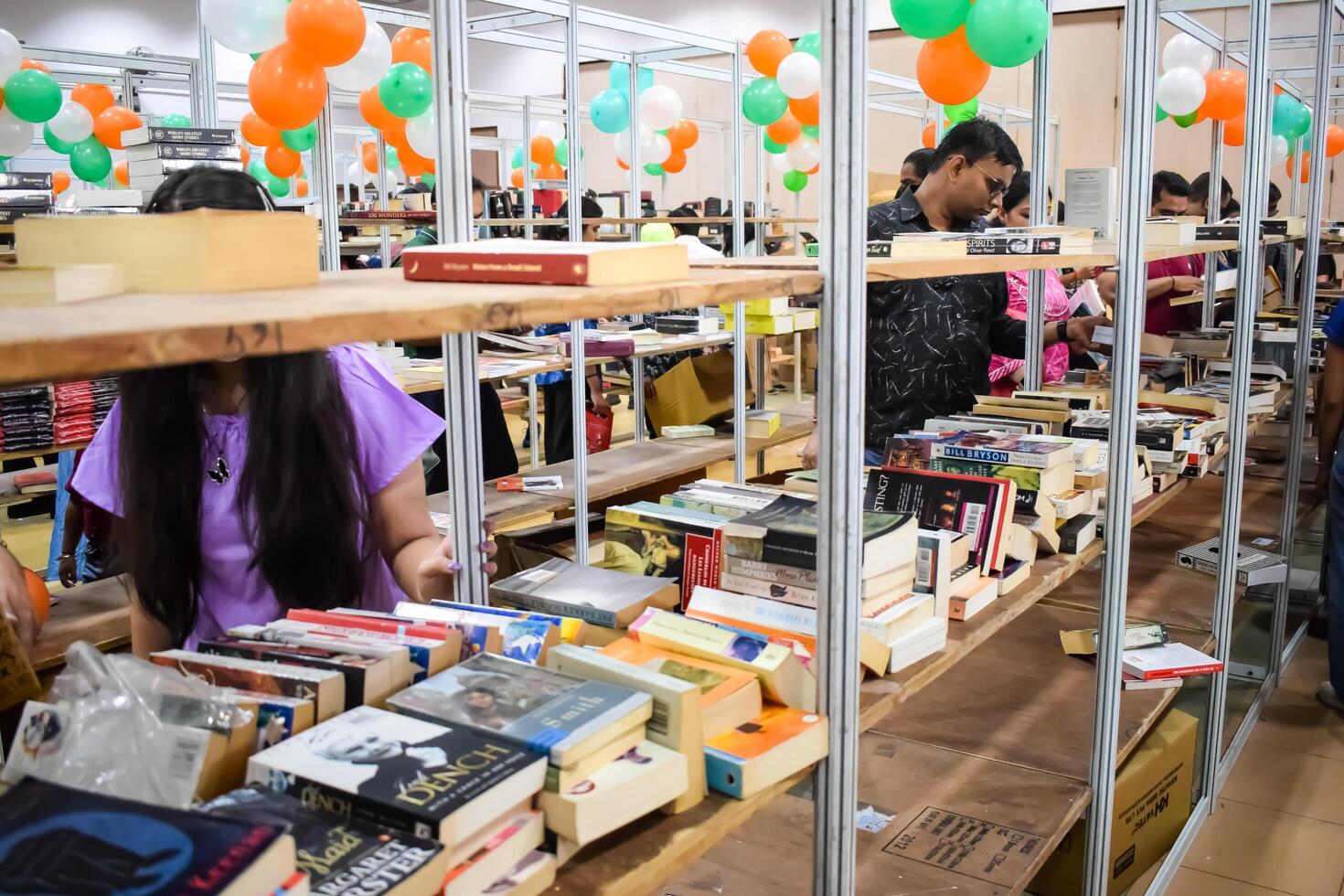 Delhi, India, February 17 2024 - Various age group people reading variety of Books on shelf inside a book-stall at Delhi International Book Fair, Books in Annual Book Fair at Bharat Mandapam complex photo