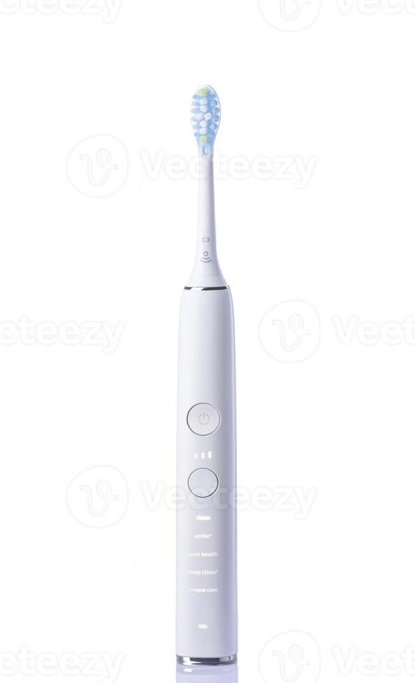 a white electric toothbrush with a green toothbrush head photo