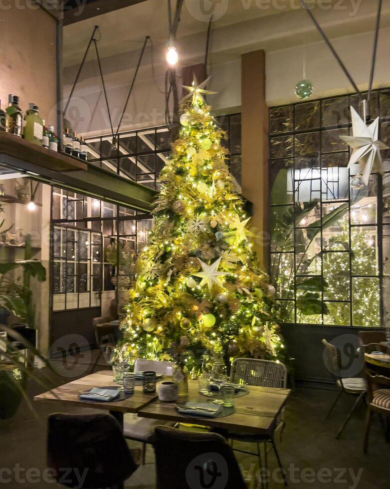 a christmas tree in a restaurant with tables and chairs photo