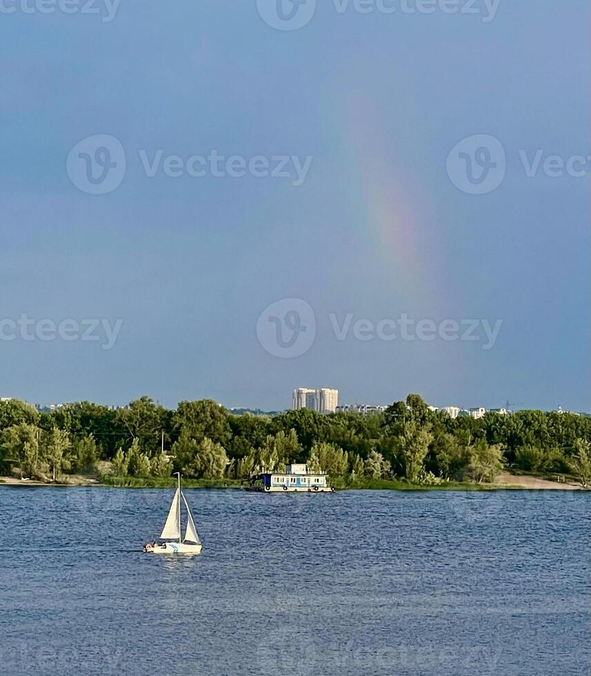 a sailboat in the water with a rainbow in the sky photo