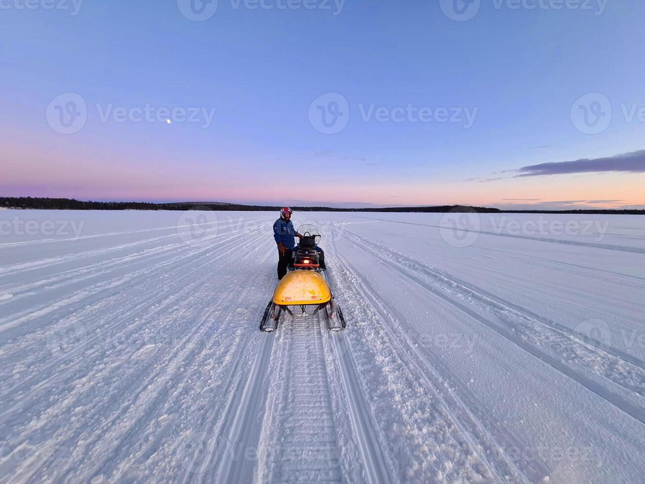 a person on a snowmobile in the middle of a large open field photo