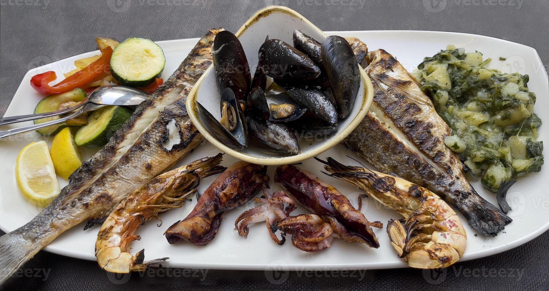 a plate of food with fish, vegetables and other items photo