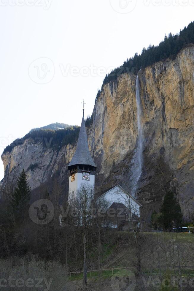 a church with a steeple and a waterfall in the background photo