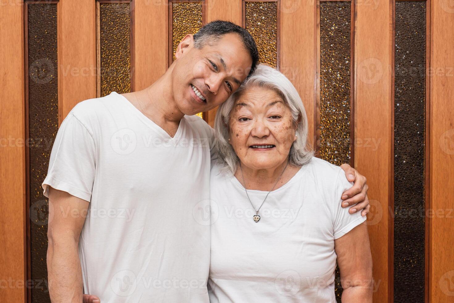 Asian mother and adult son smile and look at camera. Mother's day photo