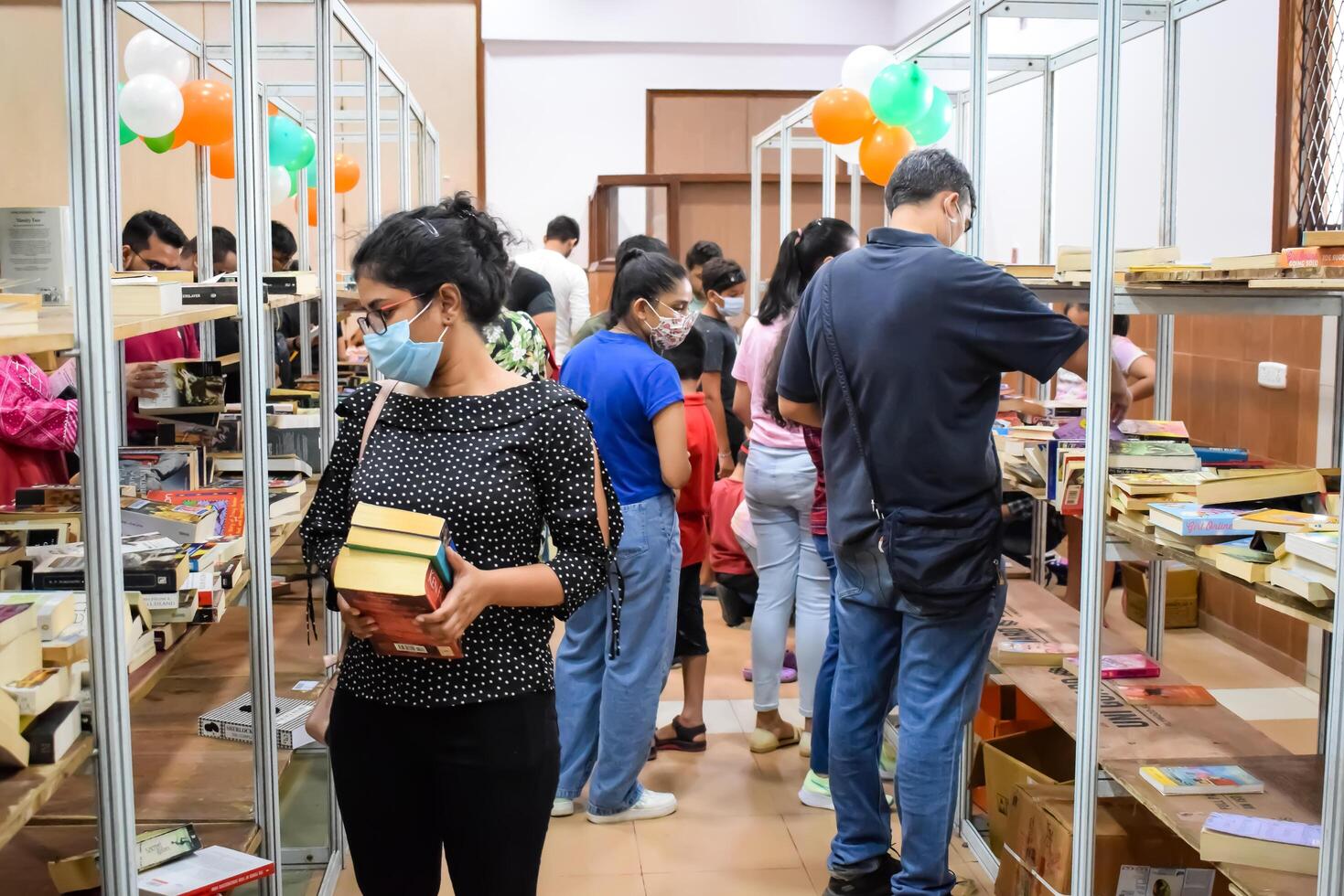 Delhi, India, February 17 2024 - Various age group people reading variety of Books on shelf inside a book-stall at Delhi International Book Fair, Books in Annual Book Fair at Bharat Mandapam complex photo