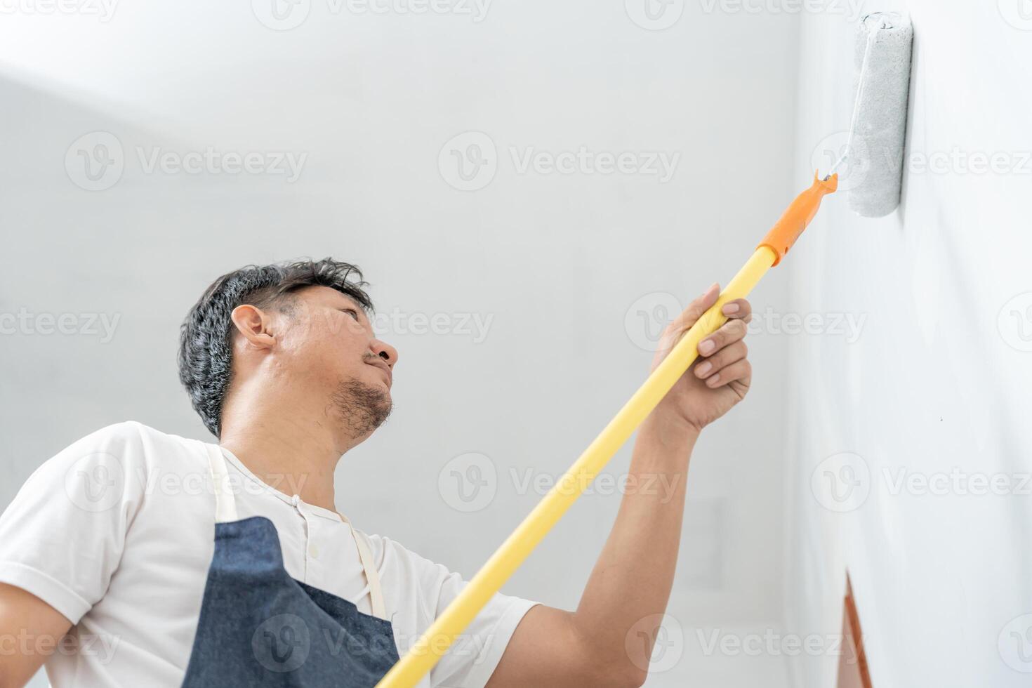 painter man, brush in hand for products to restore and paint the wall, indoor the building site of a house, wall during painting, renovation, painting, contractor, Architect, construction worker photo