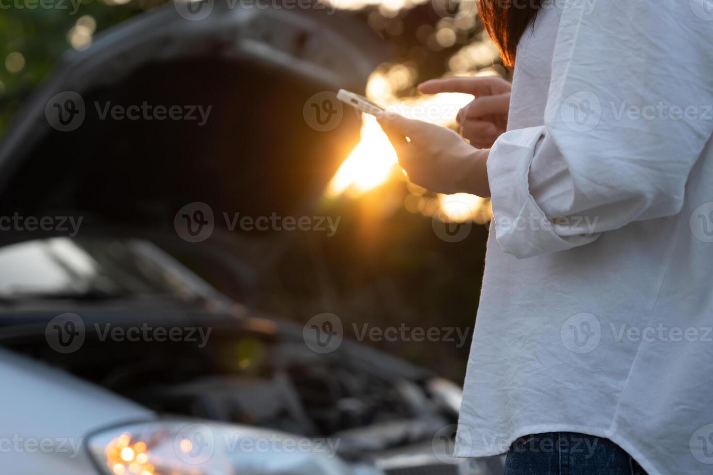 breakdown, broken car, repair. Woman uses mobile phone check insurance premiums through application due to car accident . Find garage to get car fixed during country tour, waiting for help, emergency. photo