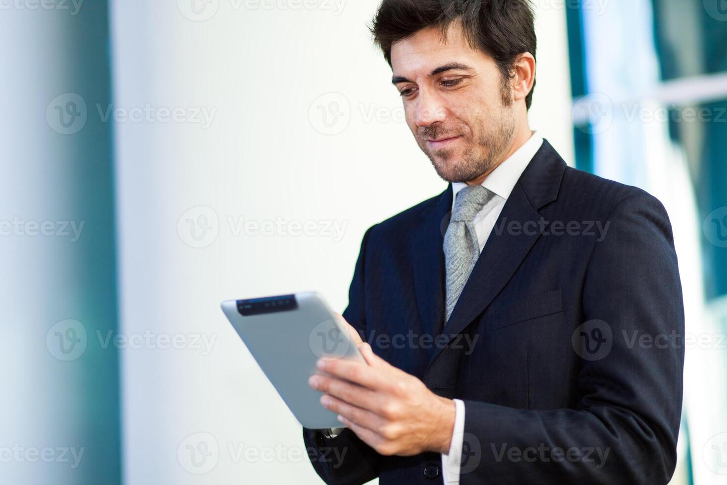 Portrait of a smiling businessman using his tablet computer photo