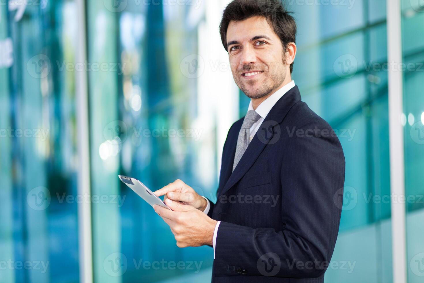 Portrait of a smiling businessman using his tablet computer photo
