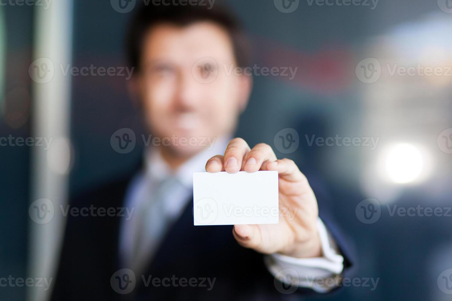 Defocused businessman showing an empty business card photo