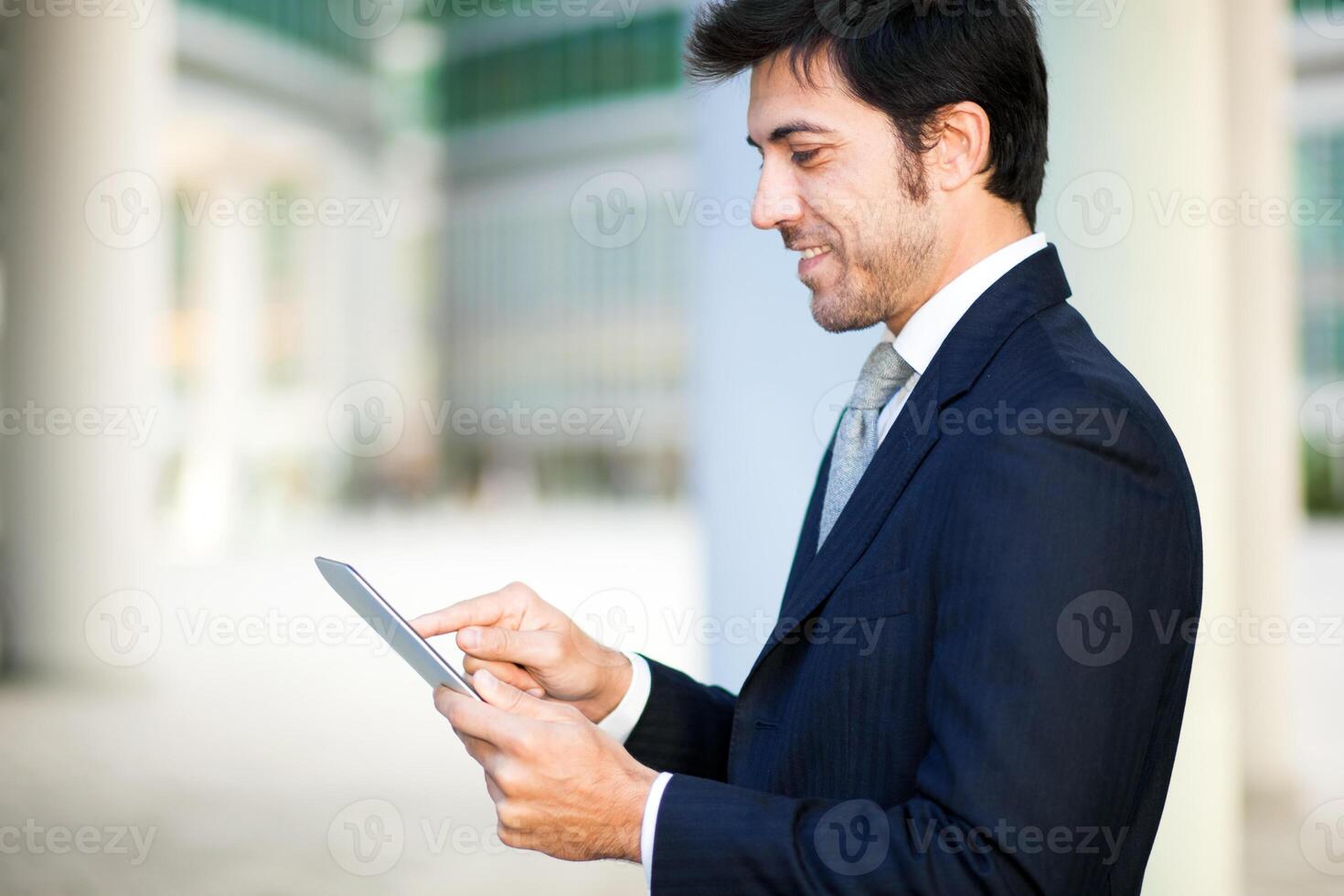 Portrait of a smiling businessman using his tablet computer photo