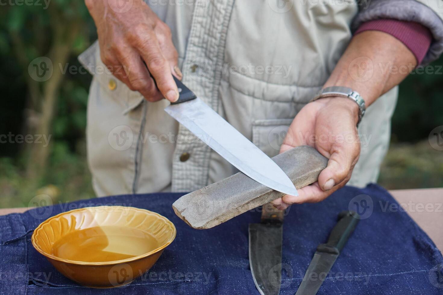 Closeup man hands sharpen knife on whetstone sharpener or grindstone. Concept, maintenance tools for cooking, make knife sharp ,not dull for long live using. Original style. photo
