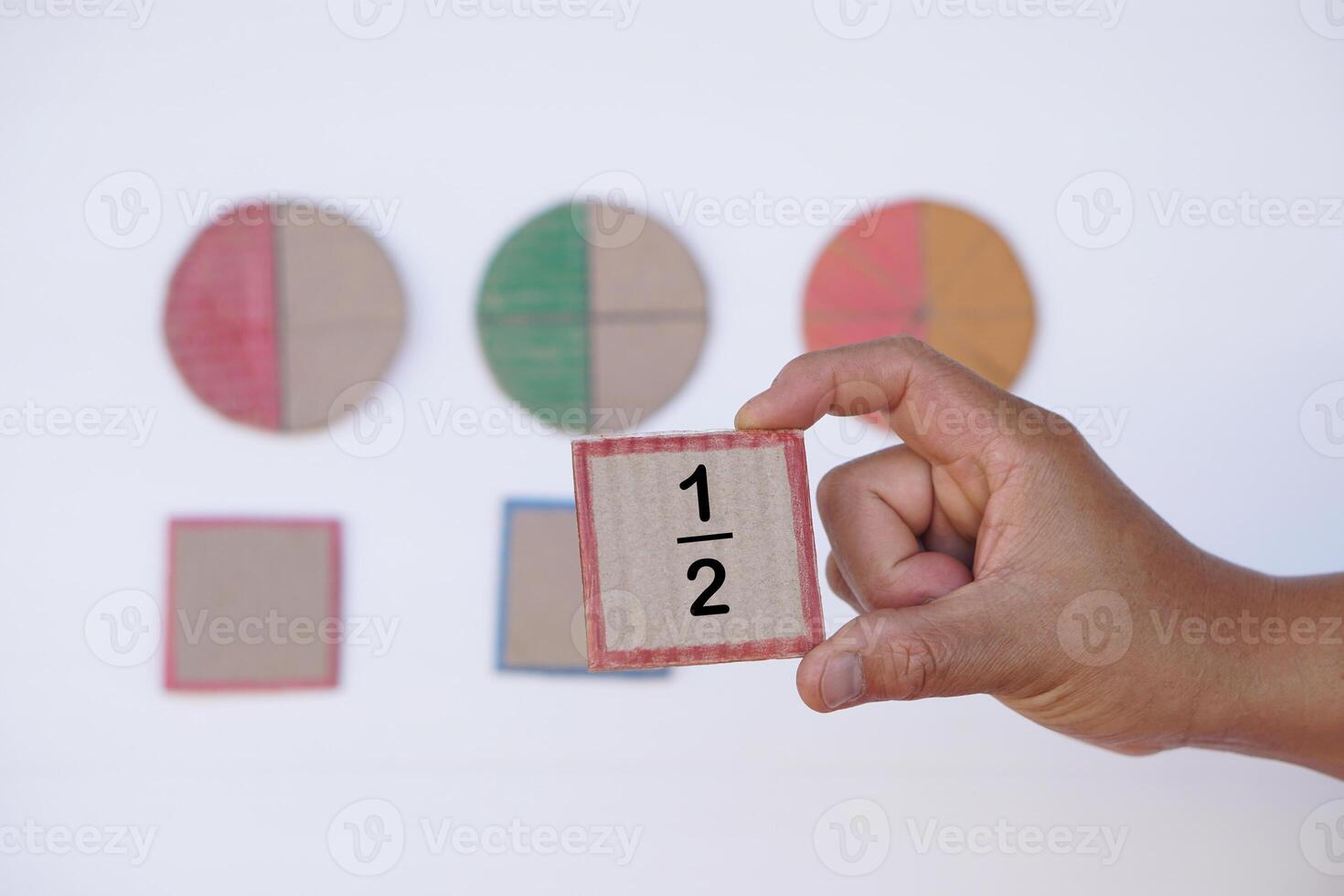 Hand hold paper card with fraction numbers. Circle paper show parts of color separation. Concept, Math teaching. Education. DIY craft as teaching aid in Math subject. photo