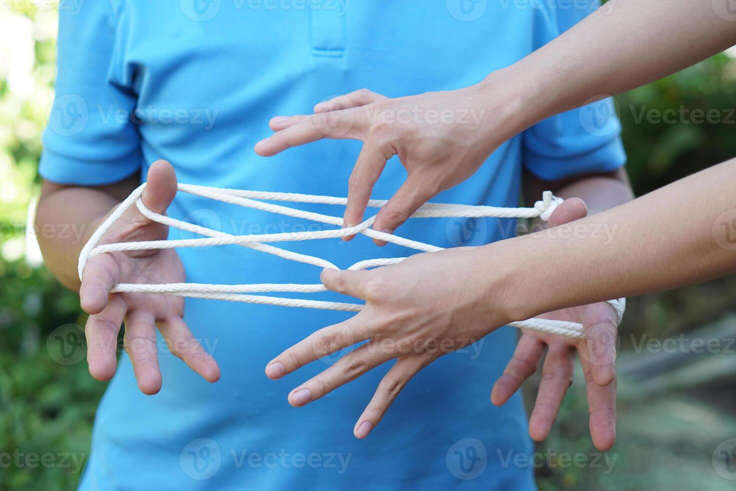 Close up two men playing with rope traditional game called cat cradle, use hands to hold  and create patterns of rope . Concept, game involving the creation of various style figures between fingers photo