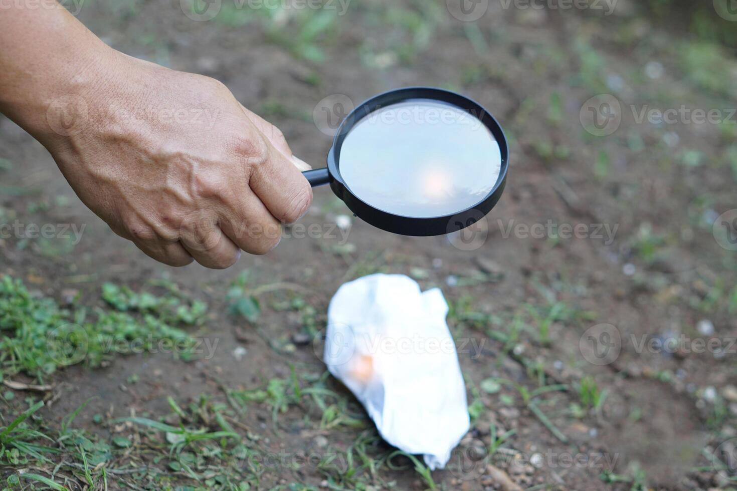 Close up hand hold magnifying glass to make fire for burning paper. Concept, Science experiment about convex lens, hold magnifying glass between the sun and tinder. Handy survival skills. photo