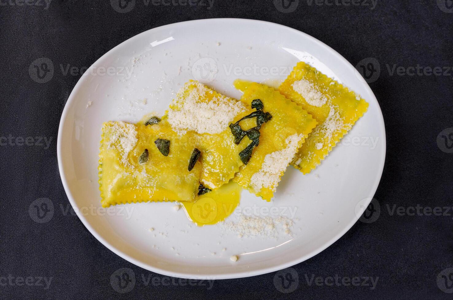 italiano Ravioles en un blanco plato con un negro antecedentes foto