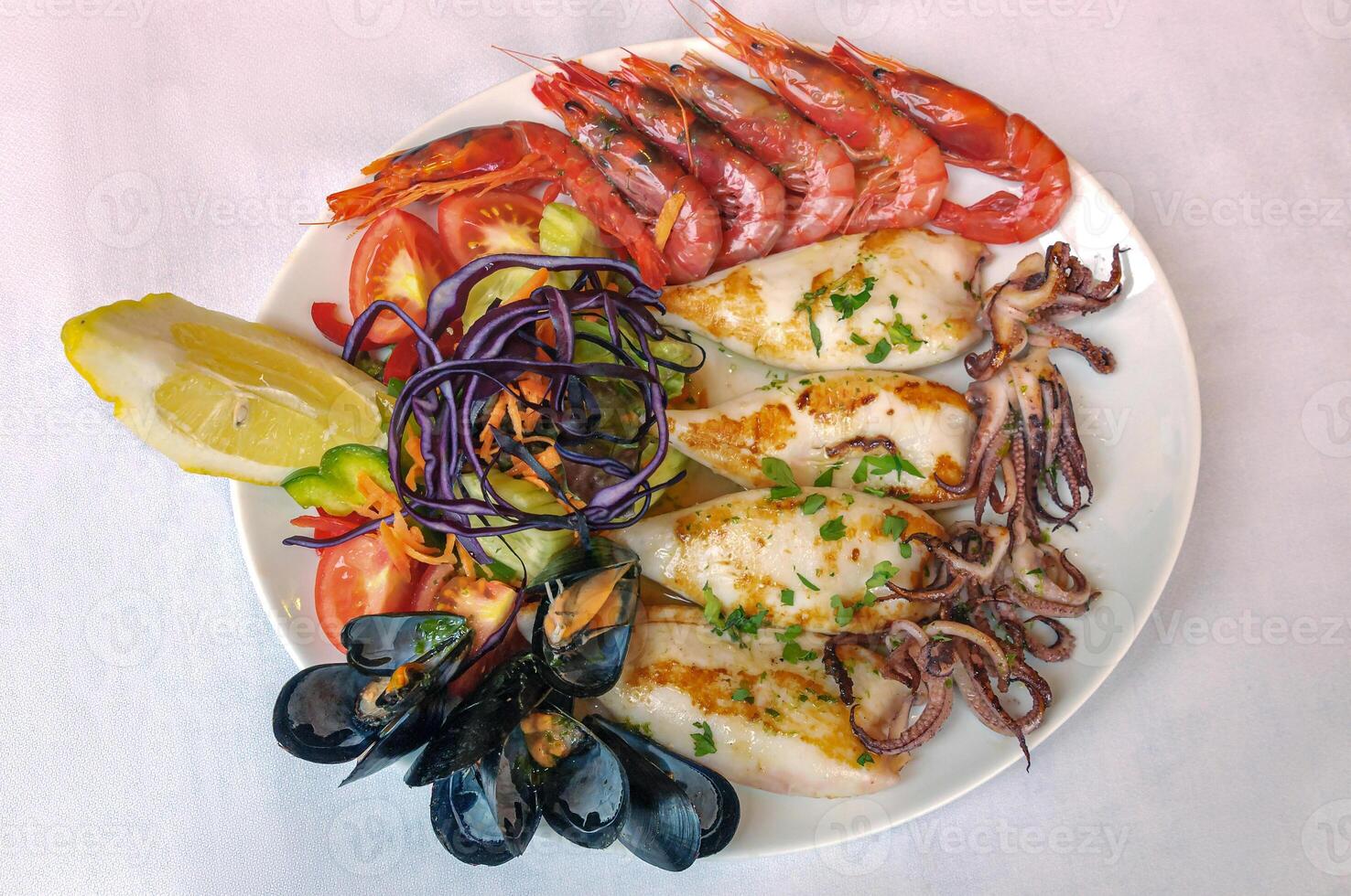 Plate with grilled seafood. Mussels, cuttlefish, shrimp, lemon photo