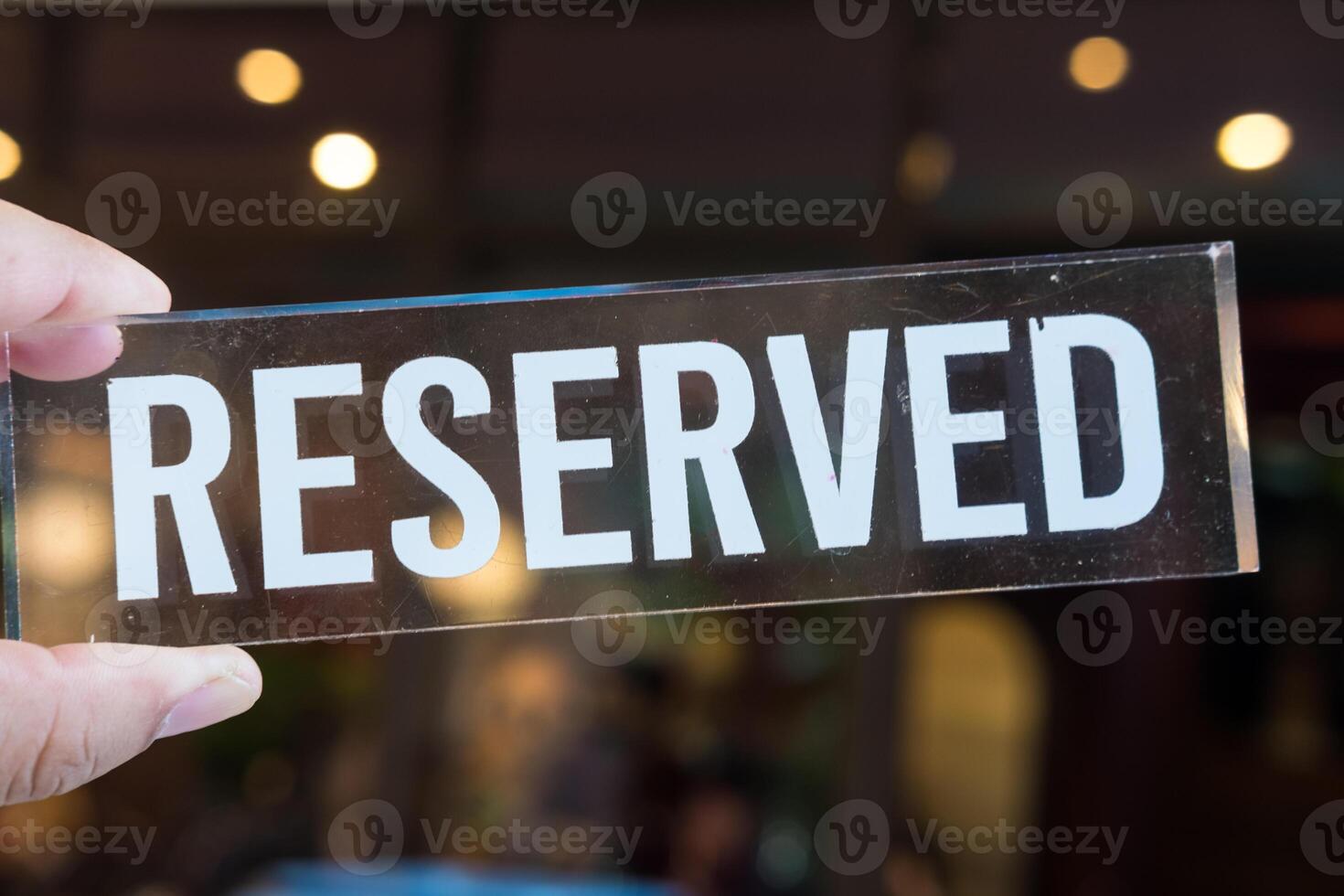 Reserved sign on hand with light bokeh background photo