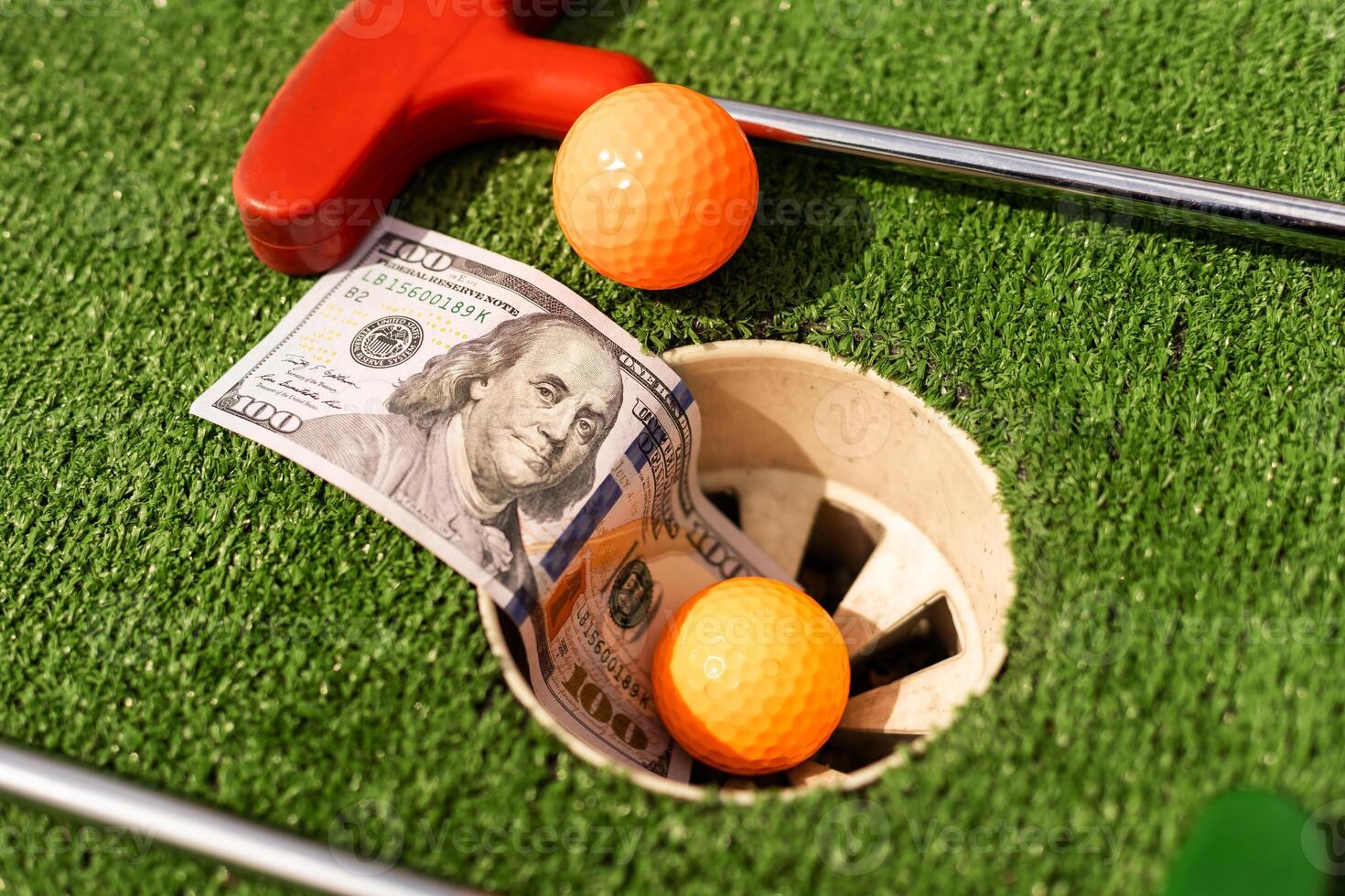 Mini Golf club, ball and money on the artificial grass photo