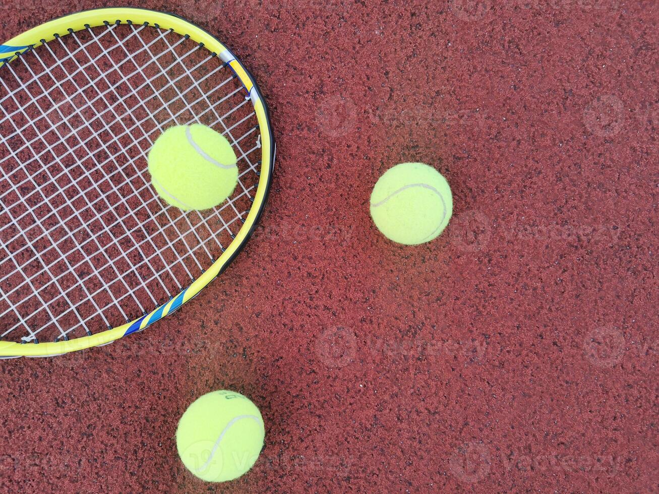 yellow tennis balls and racquet on hard tennis court surface, top view tennis scene photo